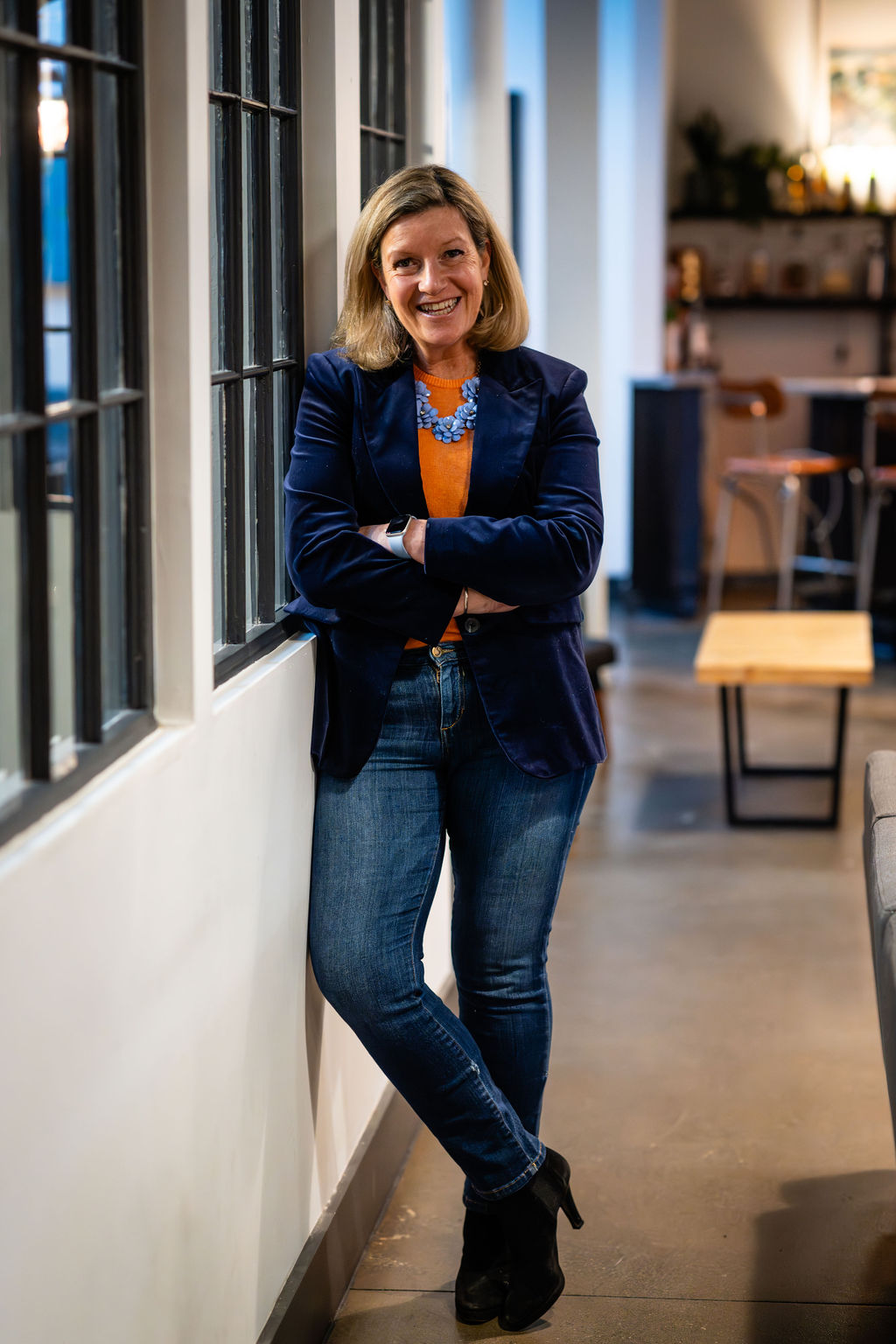 Sarah Wilkins of TA-DA standing along a wall in a cafe